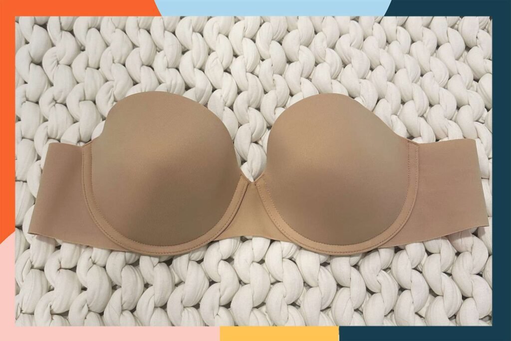 A beige classic strapless bra laying on a white background.