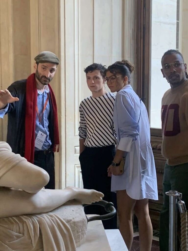 Tom Holland and Zendaya walking hand-in-hand through the Louvre Museum in Paris.