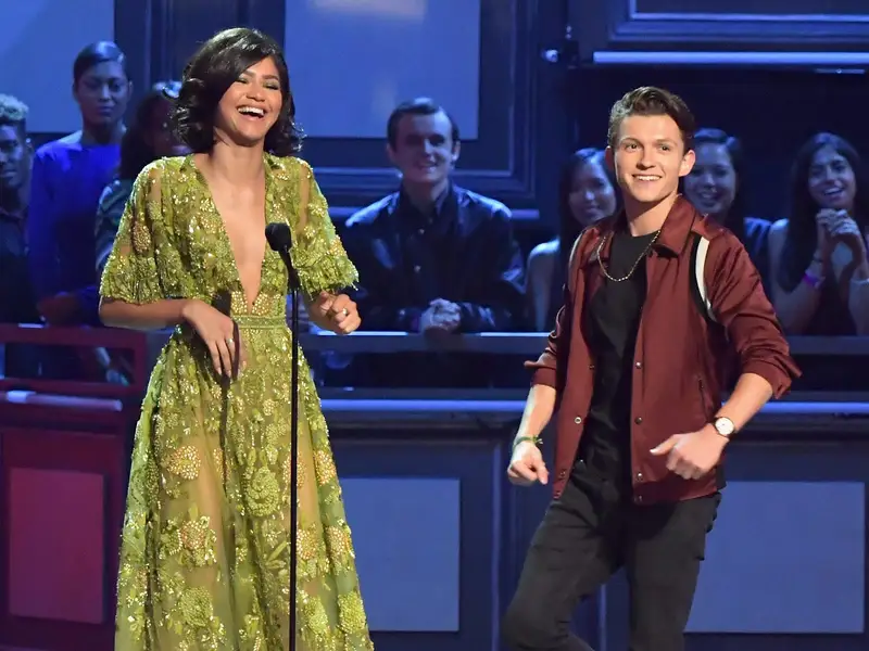 Tom Holland and Zendaya laughing together at the MTV Movie and TV Awards.